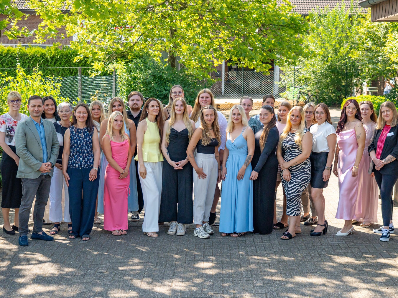 Gruppenfoto von 20 neuen Pflegefachpersonen mit KKLE-Direktorin und Geschäftsführung bei Zeugnisübergabe am 10. Juli.