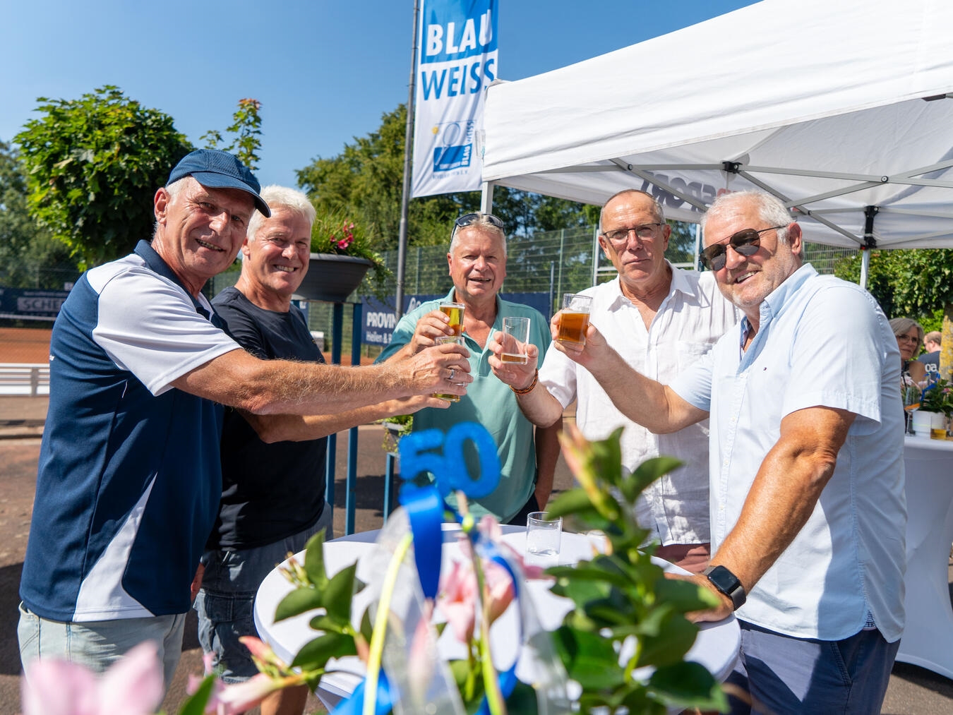 "Jubiläumsfeier 50 Jahre Kevelaerer Tennisverein, Mitglieder in Blau-Weiß feiern, Tennisplatz, Feststimmung"