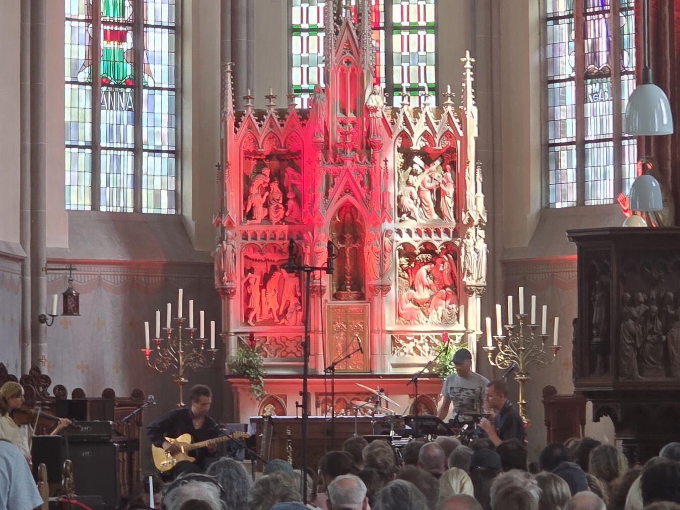 "Abel Ghekiere spielt Gitarre bei Kirchenkonzert, Musiker auf Bühne"