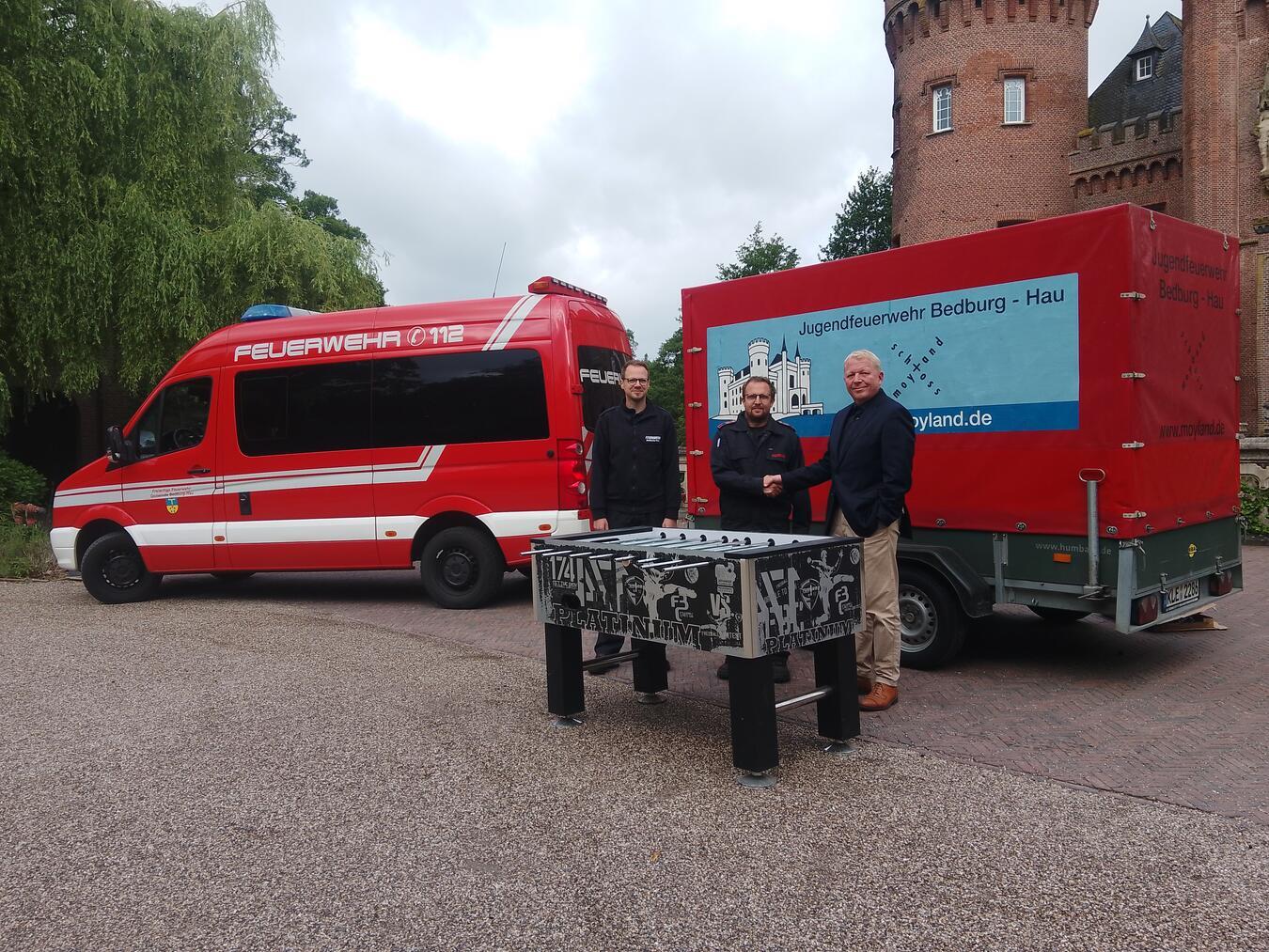 Alexander von Keyserlingk, Verwaltungsdirektor der Stiftung, übergab den Kicker an Jugendfeuerwehrwart Stefan Berns und Gemeindebrandinspektor Tobias Lamers. Foto: Feuerwehr Bedburg-Hau