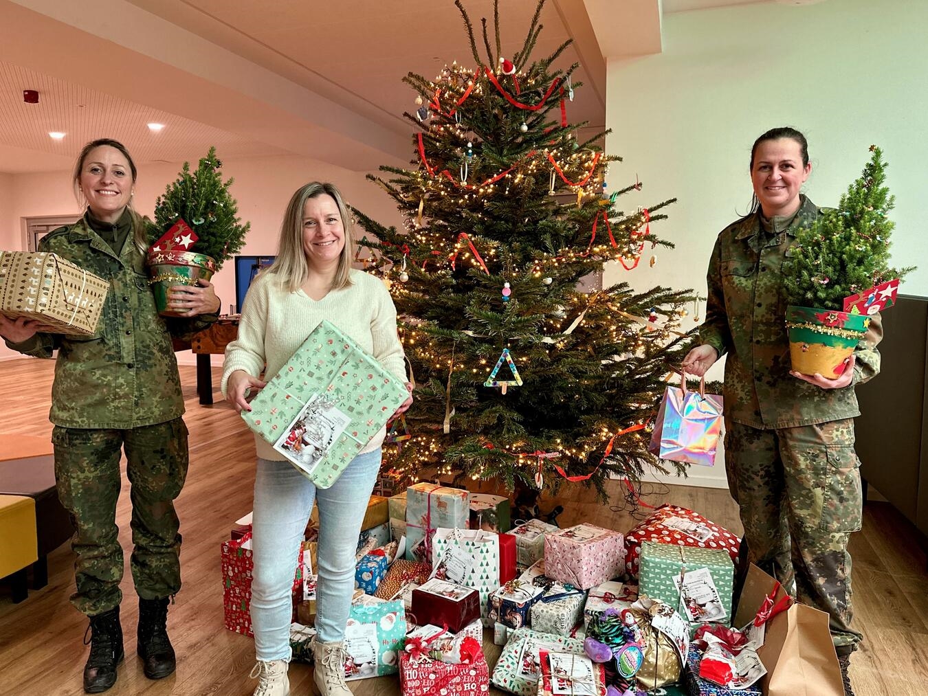 Alexandra Roolfs (l.) bringt zusammen mit ihrer Kollegin Daniela van Haal die Geschenke in der Offenen Ganztagsschule (OGS) am Förderzentrum in Kleve vorbei. Hier werden die Päckchen von OGS-Mitarbeiterin Jennifer Käppel (m.) entgegengenommen. Die OGS-Kinder haben als Dankeschön zwei kleine Tannenbäume liebevoll dekoriert. Foto: SOS Kinderdorf Niederrhein