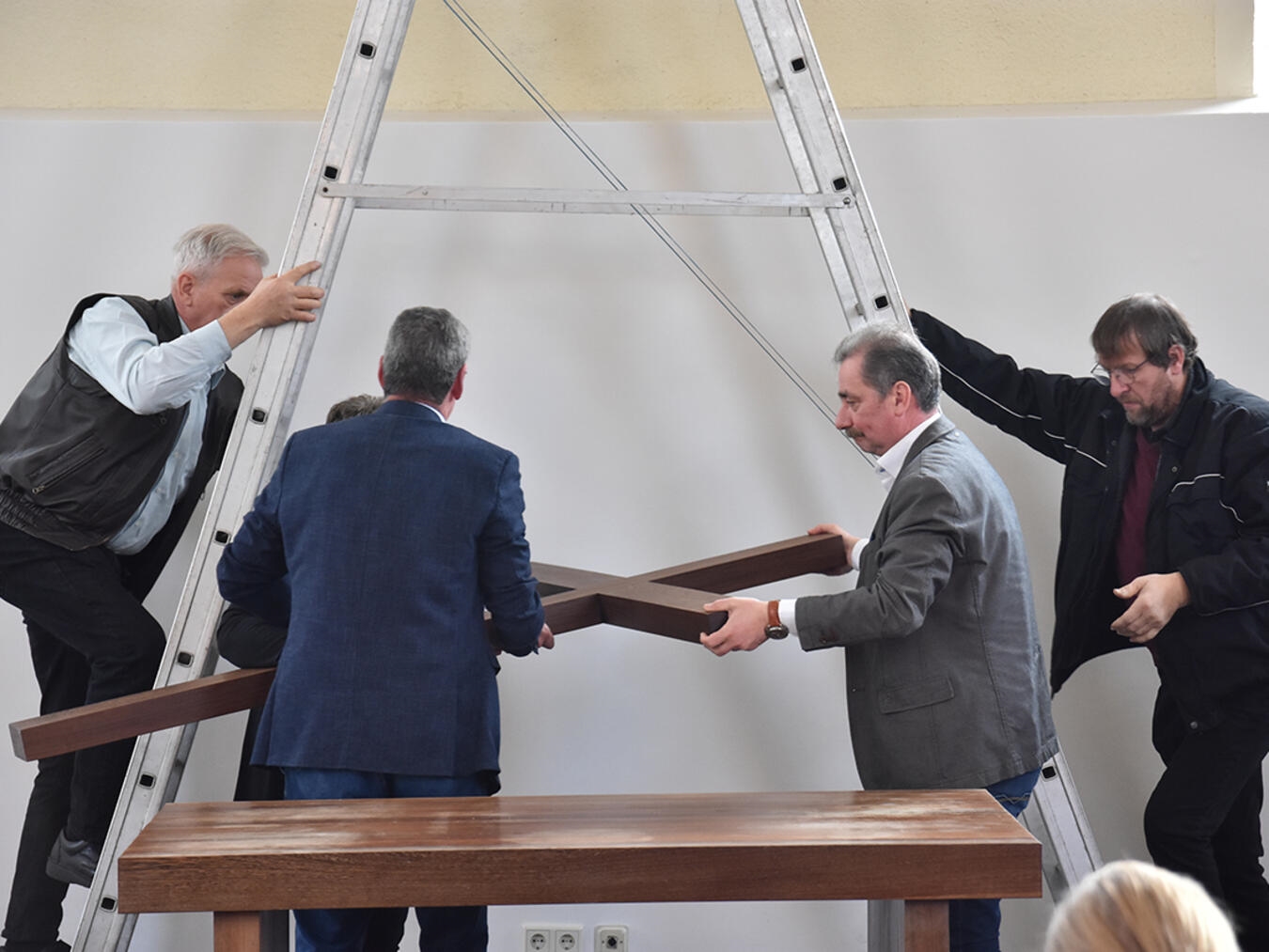 Am Ende des Entwidmungsgottesdienstes in Moyland stiegen Mitglieder des Presbyteriums auf die Leiter, nahmen das Kreuz ab und legten es bei trauriger Orgelmusik auf den Abendmahlstisch. Foto: Kirchenkreis