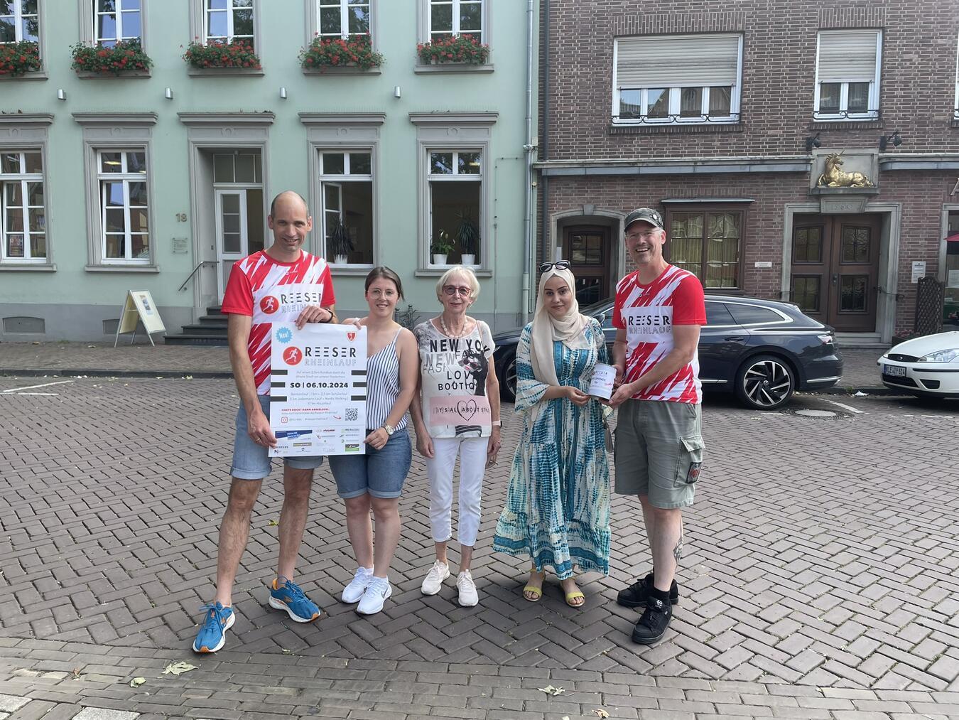Am Start- und Zielpunkt des Reeser Rheinlaufes übergaben Michael Isselburg (r.) und Tim Terhorst (l.) vom TV Rees die Spenden an Helga Häsel (Bildmitte), Shkurte Doci und Worod Alazawi. Foto: TV Rees
