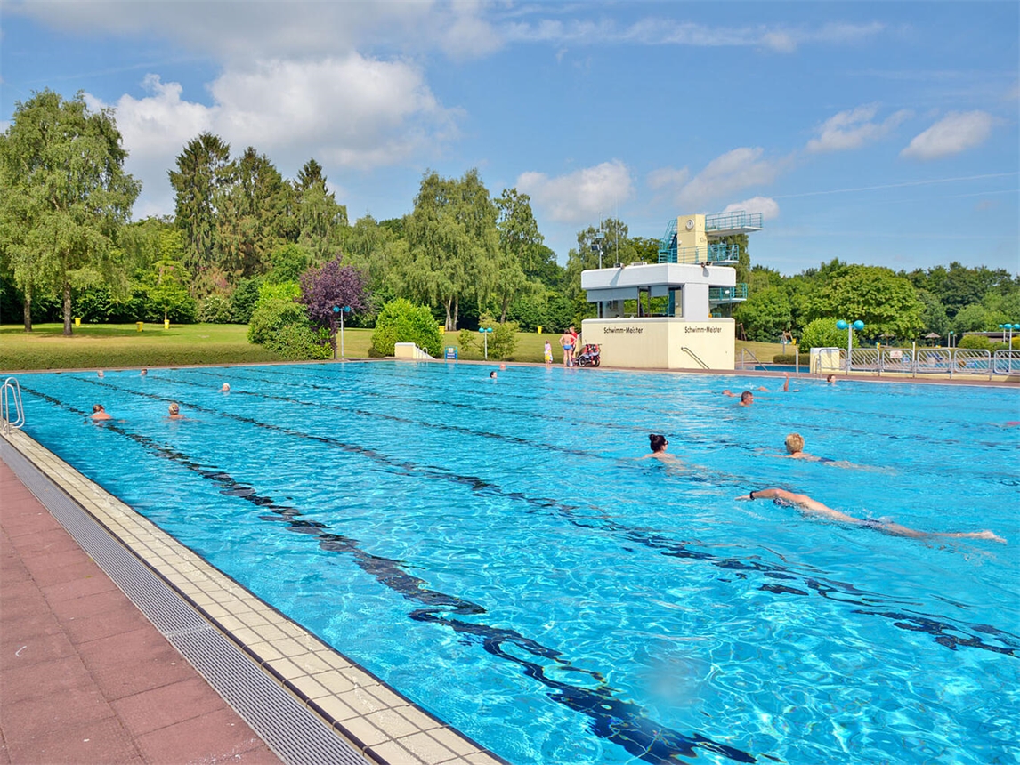 "Schwimmer im Freibad zieht letzte Bahnen an sonnigem Herbsttag, Außenbereich, Schwimmen, Saisonende"