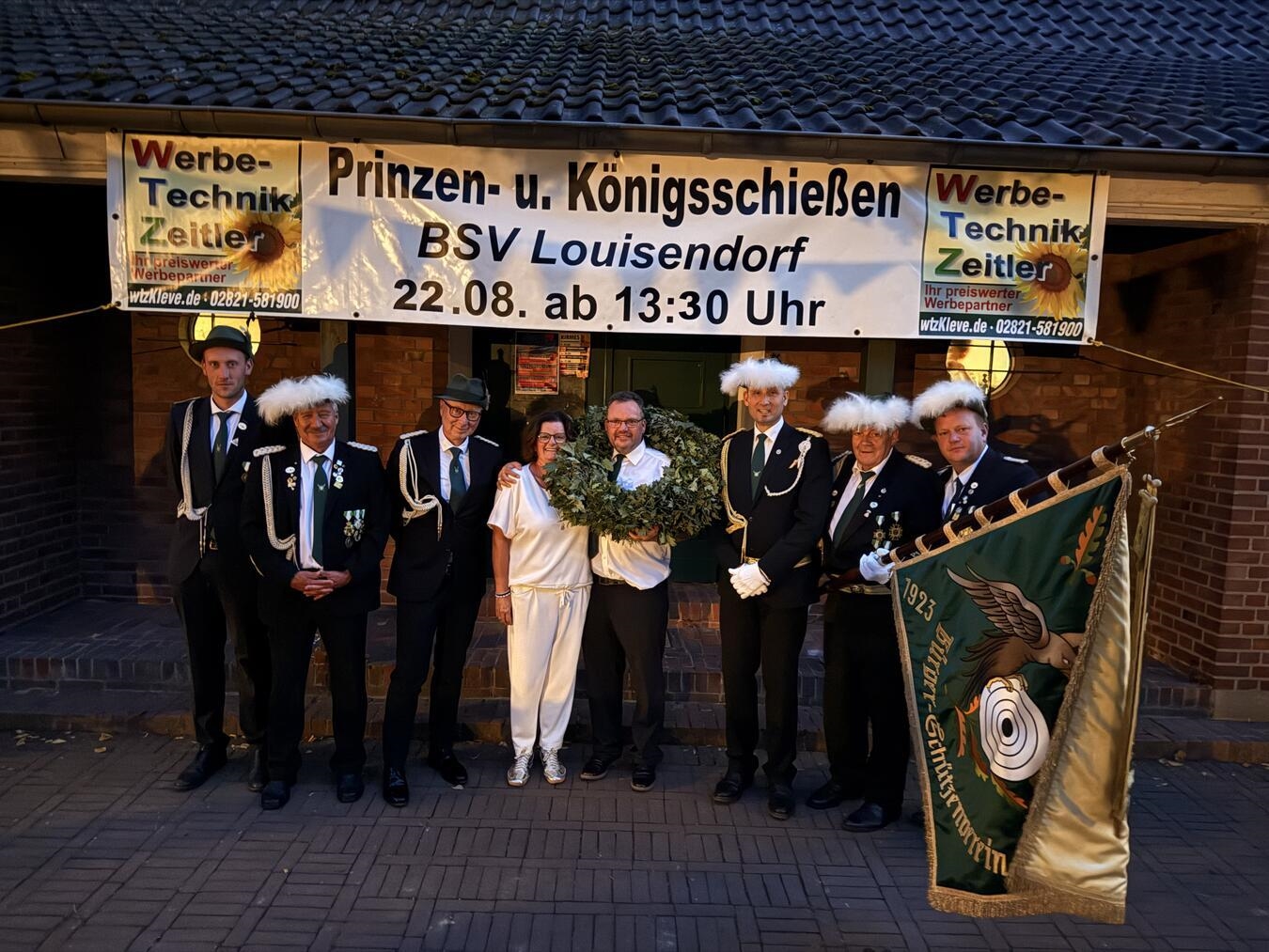 "Andreas und Melanie Mohn als Königspaar der Bürgerschützen Louisendorf, feierlich gekleidet, lächeln in die Kamera."