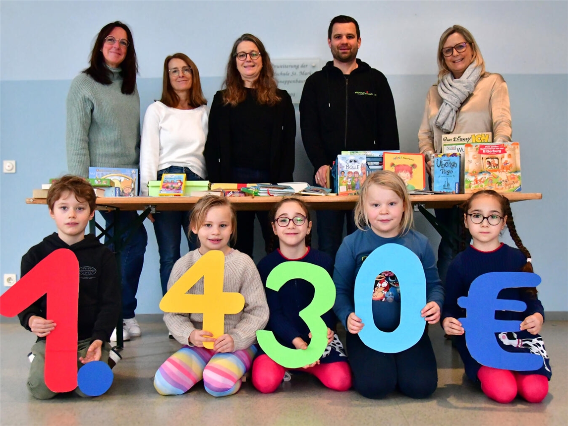 Anke Hüskes (v.l.n.r.), Bianka Lehnen, Veronika Schüßler und Manuela Witzke übergaben Peter Goemans vom Verein Stehaufmännchen die Spende. Die Kinder aus der OGS hielten die Spendensumme hoch. Foto: Caritas