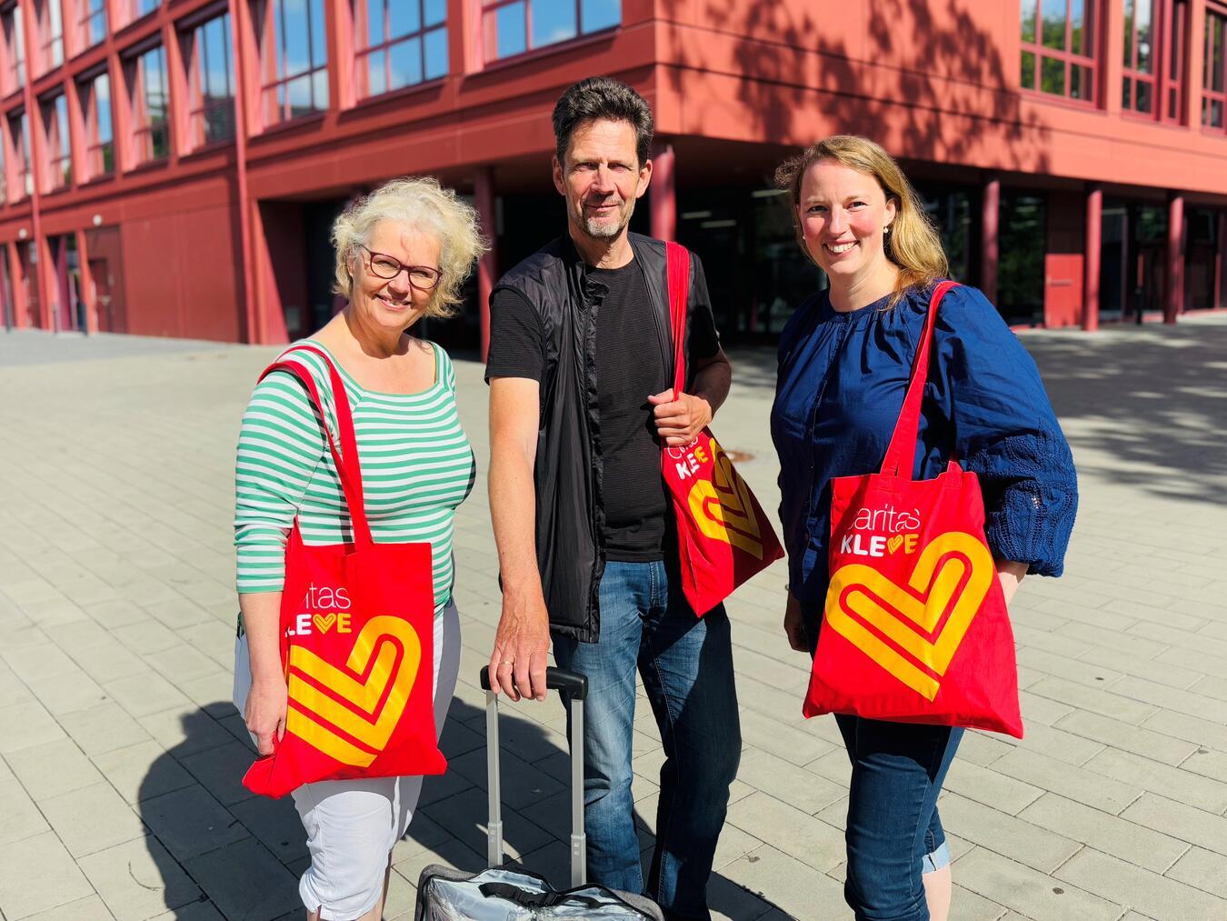 Annette Büscher (l.) und Anne-Kathrin Lehmann vom Caritasverband Kleve mit Ralf Geerlings vor der Gesamtschule Emmerich. Alle drei unterstützen einmal in der Woche Schüler der Gesamtschule. Foto: CV Kleve