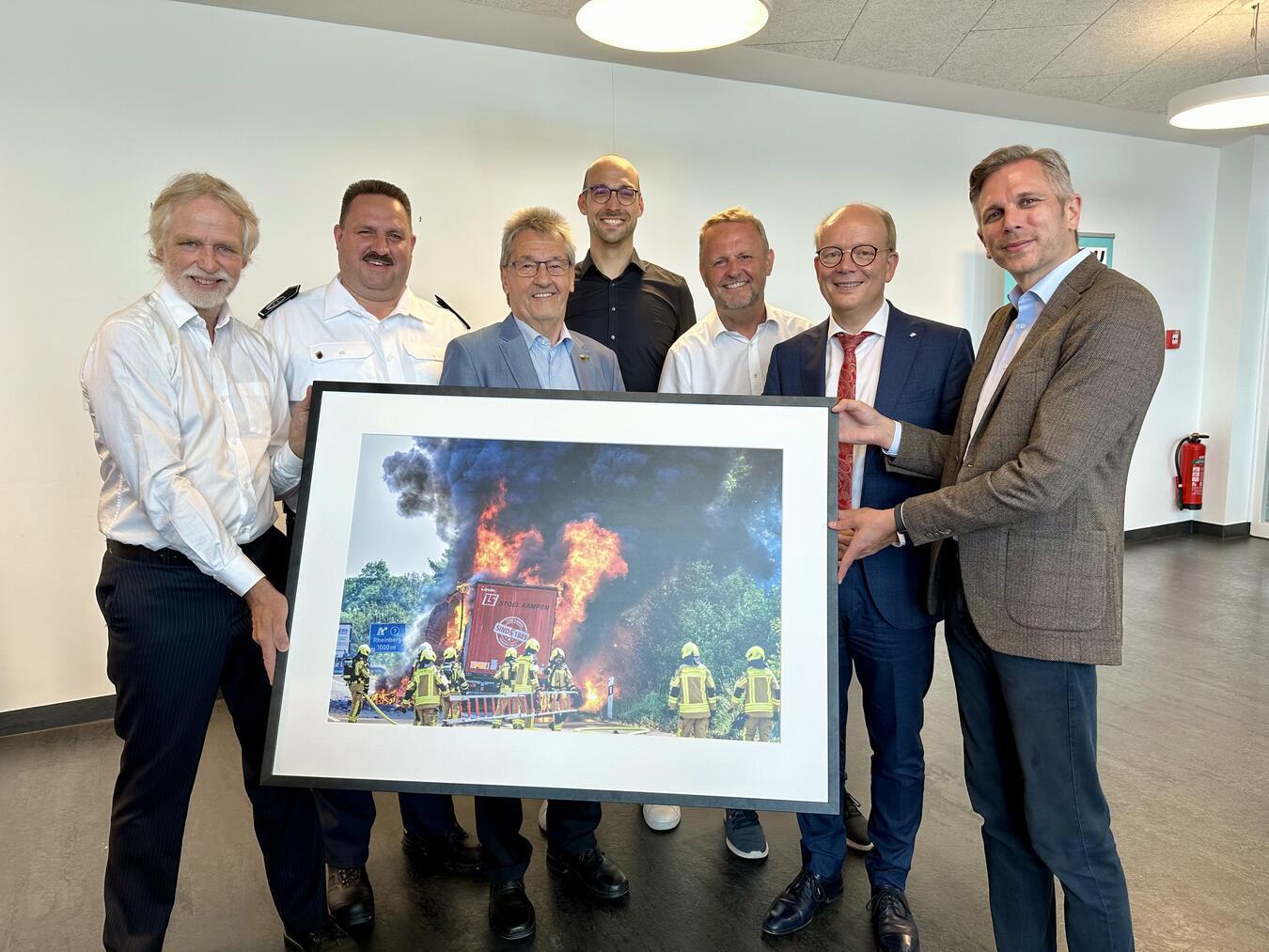 LKW-Brand auf der A57 beim Pressefoto des Jahres Arnulf Stoffel (l.) hat die beeindruckende Aufnahme gemacht, die Landtagspräsident André Kuper (2.v.r.) nun offiziell der Freiwilligen Feuerwehr Alpen überreichte. Sie war beim NRW-Pressefoto des Jahres in die engere Auswahl gekommen.NN-Foto: SP