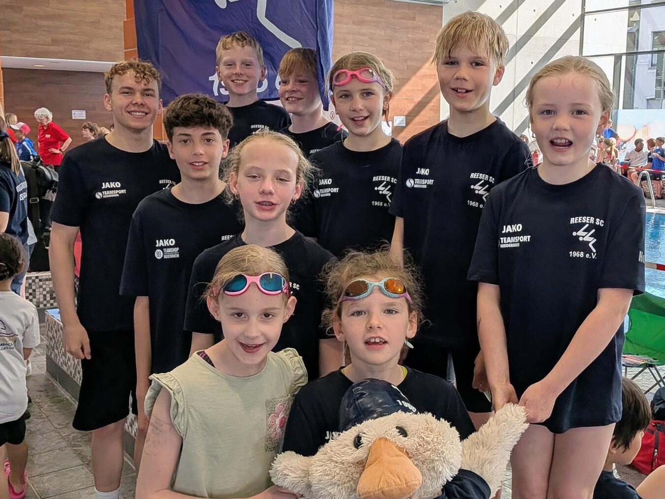 "Kinderschwimmer mit Maskottchen Schwimmbert beim Wettkampf, Unterstützung und Freude, Schwimmen lernen"