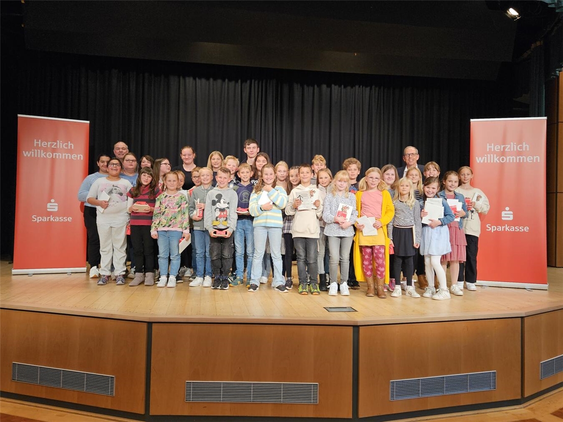 Auch im vergangenen Jahr begeisterten Schüler beim 42. Schülervorlesewettbewerb mit „Stöckskes“ in Straelener Mundart das Publikum und die Jury. Das Bild zeigt Thomas van den Bongard (re) von der Sparkasse Rhein-Maas, Bernd Heines (li) vom Kulturring und die teilnehmenden Schüler des Jahres 2024. Foto: Kulturring Straelen