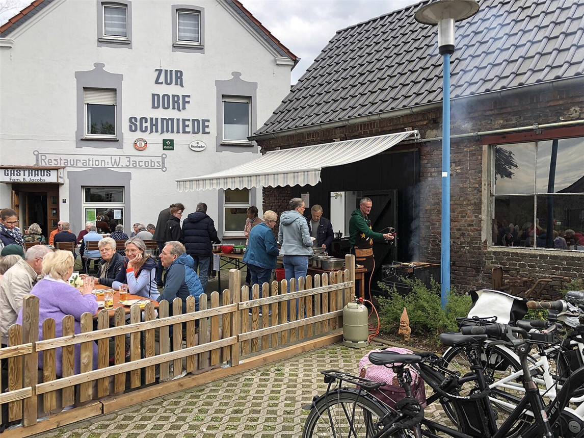 "Radfahrer genießen Frühlingssonne im Biergarten beim Angrillen vor Dorfschmiede Till-Moyland."