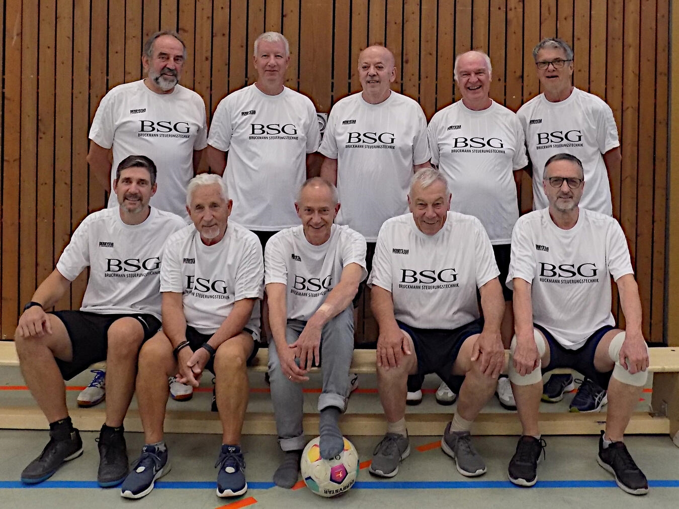 "Spieler der Behinderten-Sport-Gemeinschaft beim Hallentennis-Kick in Turnhalle, unterstützt von Trikotsponsor Bruckmann Steuerungstechnik."
