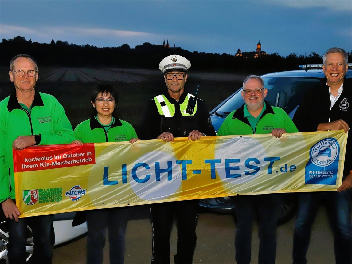 Auf dem diesjährigen Foto setzen neben Peter Baumgarten, Thomas Hermes und René Gravendyk auch Falk Neutzer, Geschäftsführer der Verkehrswacht Kreis Kleve, und Vorstandsmitglied Mona Neutzer ein sichtbares Zeichen für die Aktion. Vor der abendlichen Silhouette Kleves mit der beleuchteten Schwanenburg passt die Aufnahme zum Beginn der dunklen Jahreszeit. Die gemeinsame Botschaft lautet: Licht prüfen lassen, sichtbar bleiben und sicher durch Herbst und Winter kommen. Foto: Falk