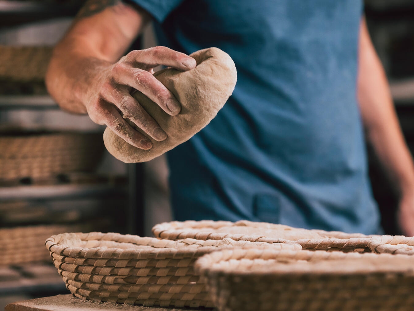 Bäcker bei der Arbeit in traditioneller Bäckerei, frisches Brot auf dem Tisch, unterstützt faire Löhne und lokales Handwerk.