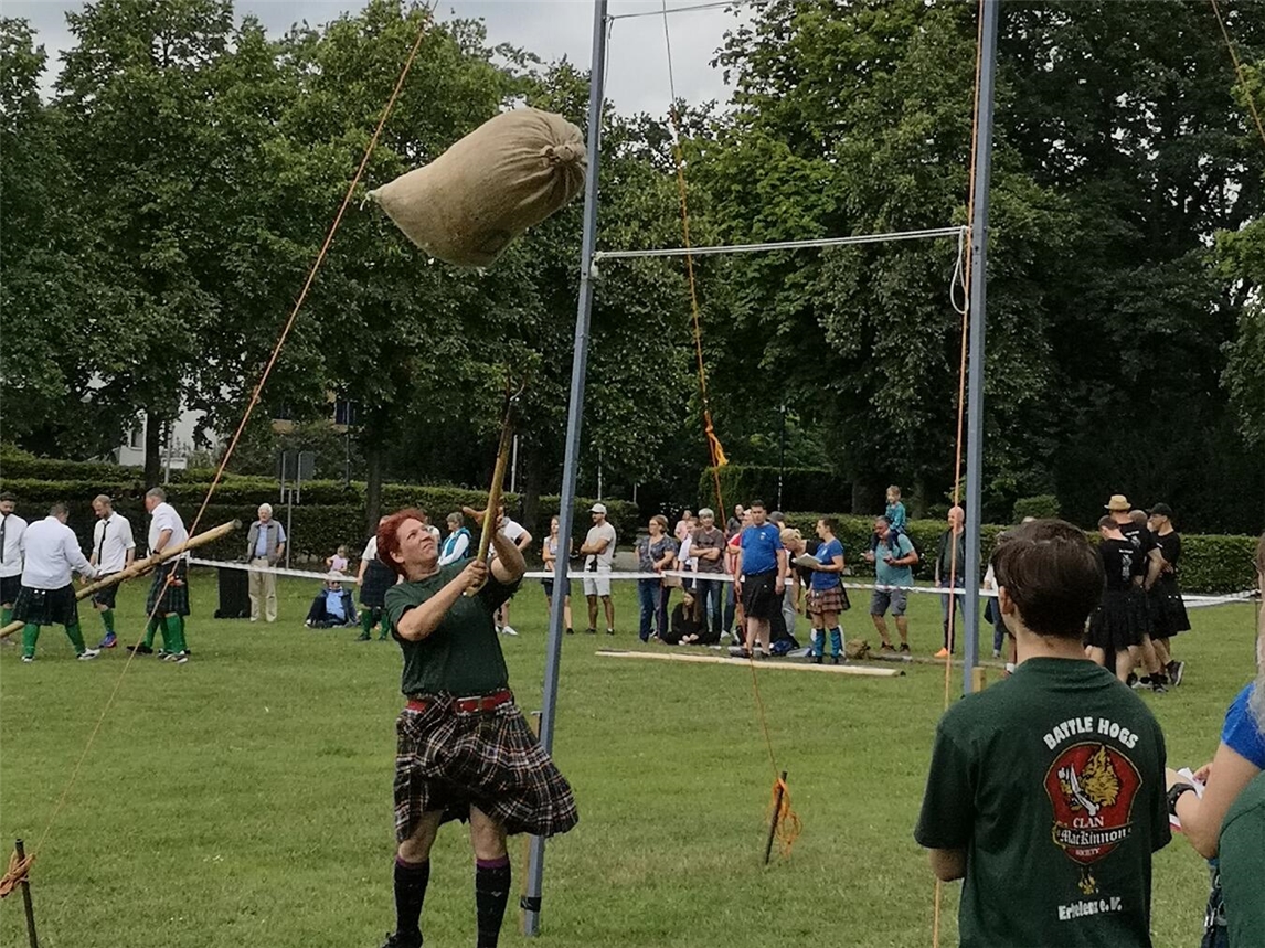 "Teilnehmer bei Highland Games Wesel wirft Baumstamm, traditionelle schottische Sportveranstaltung"