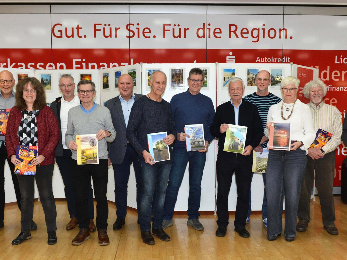 Bei der Vorstellung des Sparkassen-Kalenders 2025: Thomas Müller (6.v.l.) und Uwe Merling (1.v.r.) (beide Sparkasse) mit den Fotografen: Christiane Bienemann, Hans-Ulrich Holtkamp, Zbigniew Chojnacki, Hans-Wilhelm Heek, Thomas Arntz, Norbert Verhoeven, Beate Klopp, Johannes Janßen, Diana Freund, Andreas Wolff und Roland van Bremen (bei der Übergabe terminlich verhindert: Thomas Rauers, Bruno Langer, Thomas Hillebrand, und Klaus Neumann). Foto: Klaus-Dieter Stade