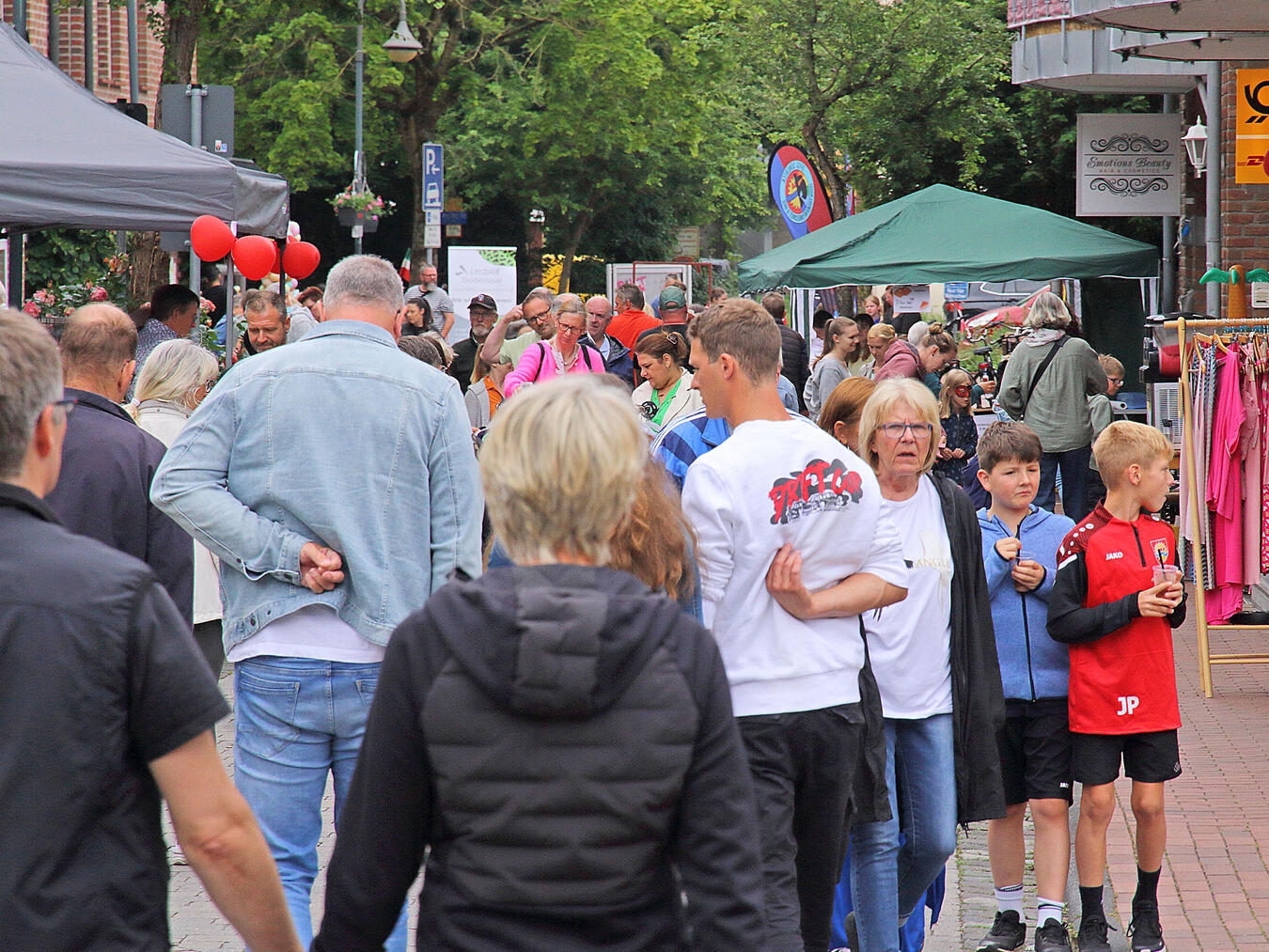 "Besucher stöbern auf dem belebten Brunnenmarkt der Sonsbecker Werbegemeinschaft, Menschenmenge und Marktstände bei Sonnenschein."