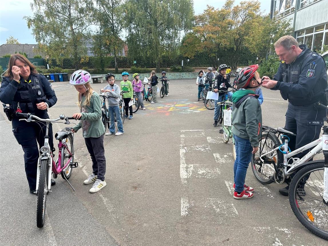 Beließ es nicht bei der Prüfung der Verkehrssicherheit, sondern führte notwendige Reparaturen an den Fahrrädern sofort durch: Das Team der Kreispolizei und des Bereichs Ordnung bei der Stadt Geldern prüfte auch den richtigen Sitz der Helme – hier auf dem Schulhof der Sankt Antonius Schule in Hartefeld.Foto: hvs