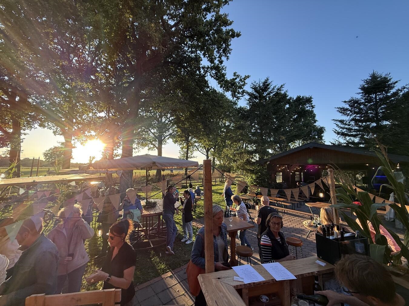 "Offener Hofabend am Klappboomshof bei Sonnenuntergang, Besucher erkunden den Hof"