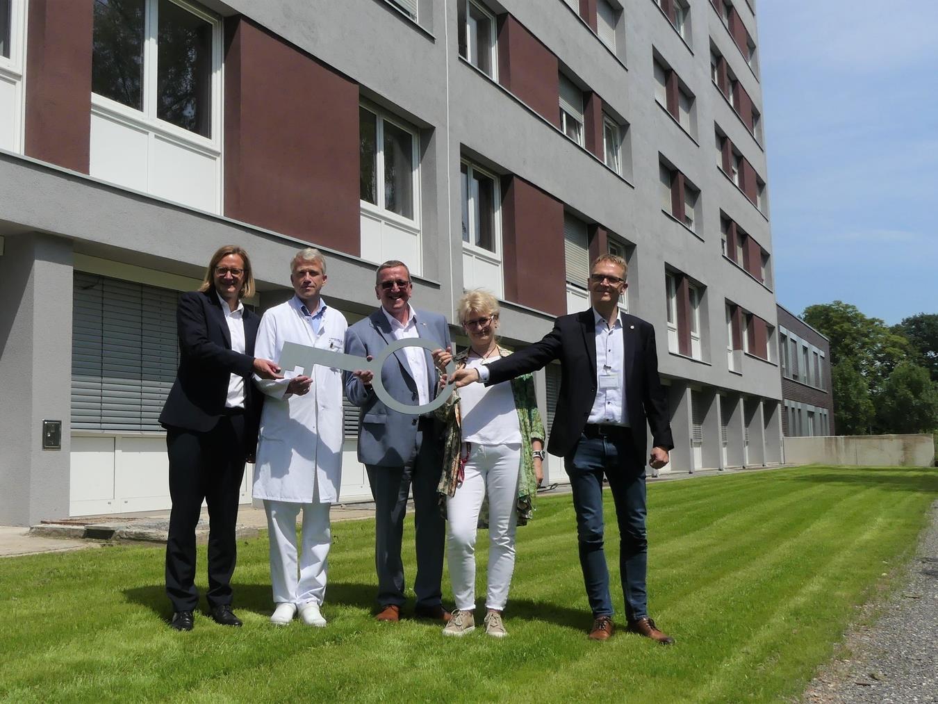 Bettina Gande vom Baumanagement übergibt symbolisch den Schlüssel vor dem frisch sanierten Bettenhaus an (v.l.) Dr. Conrad Middendorf, Dr. Martin Grummel, Josef Lübbers und Clemens Roeling.Foto: SBK/privat.
