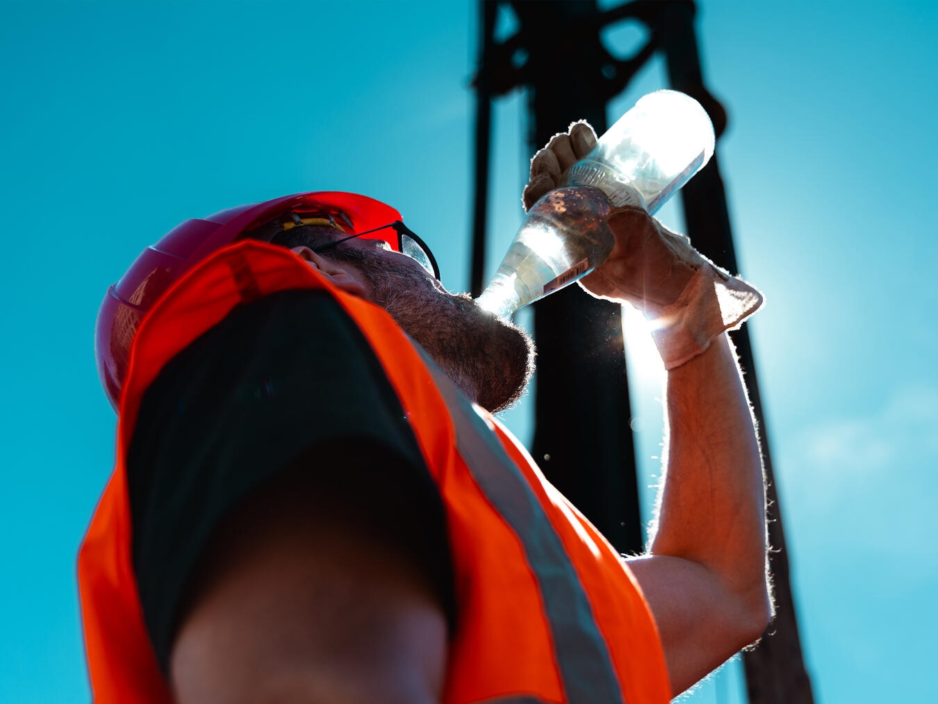 Arbeiter in Sommerhitze trinkt Wasser, IG BAU Duisburg-Niederrhein betont Arbeitgeberpflicht zur Getränkebereitstellung.