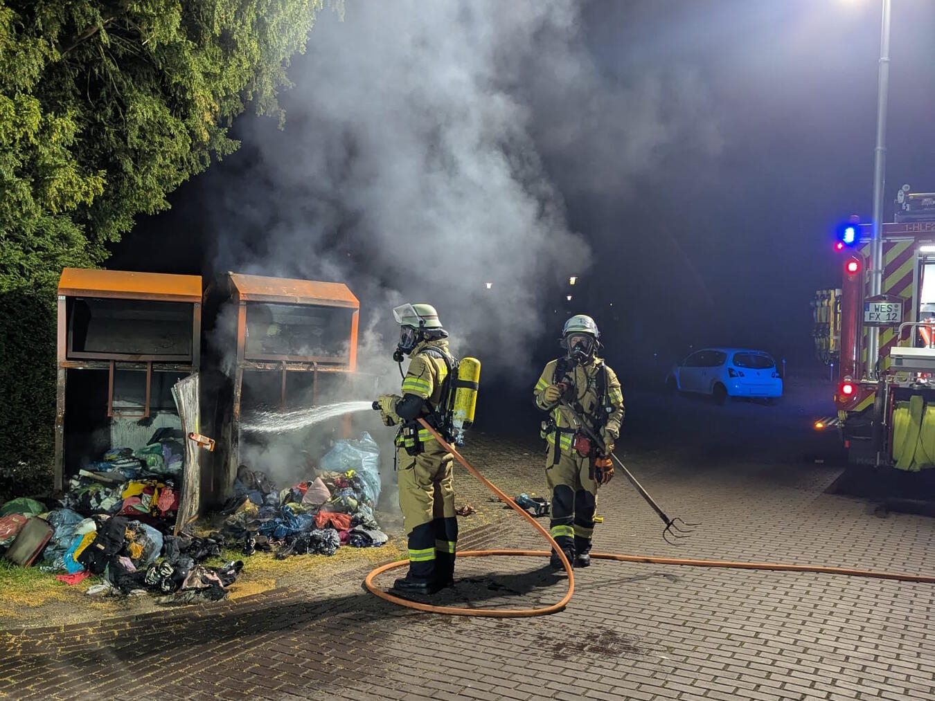 "Brennende Altkleidercontainer am Westwall, Flammen und Rauch, Umweltverschmutzung"