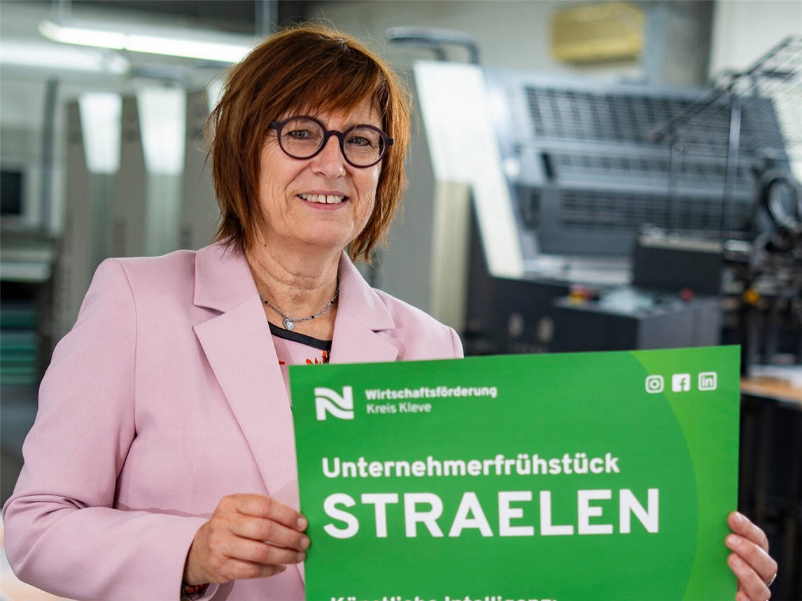 Brigitte Jansen, Geschäftsführerin der Wirtschaftsförderung Kreis Kleve, präsentiert das Plakat mit der Einladung zum Unternehmerfrühstück in Straelen.Foto: WfG Kreis Kleve