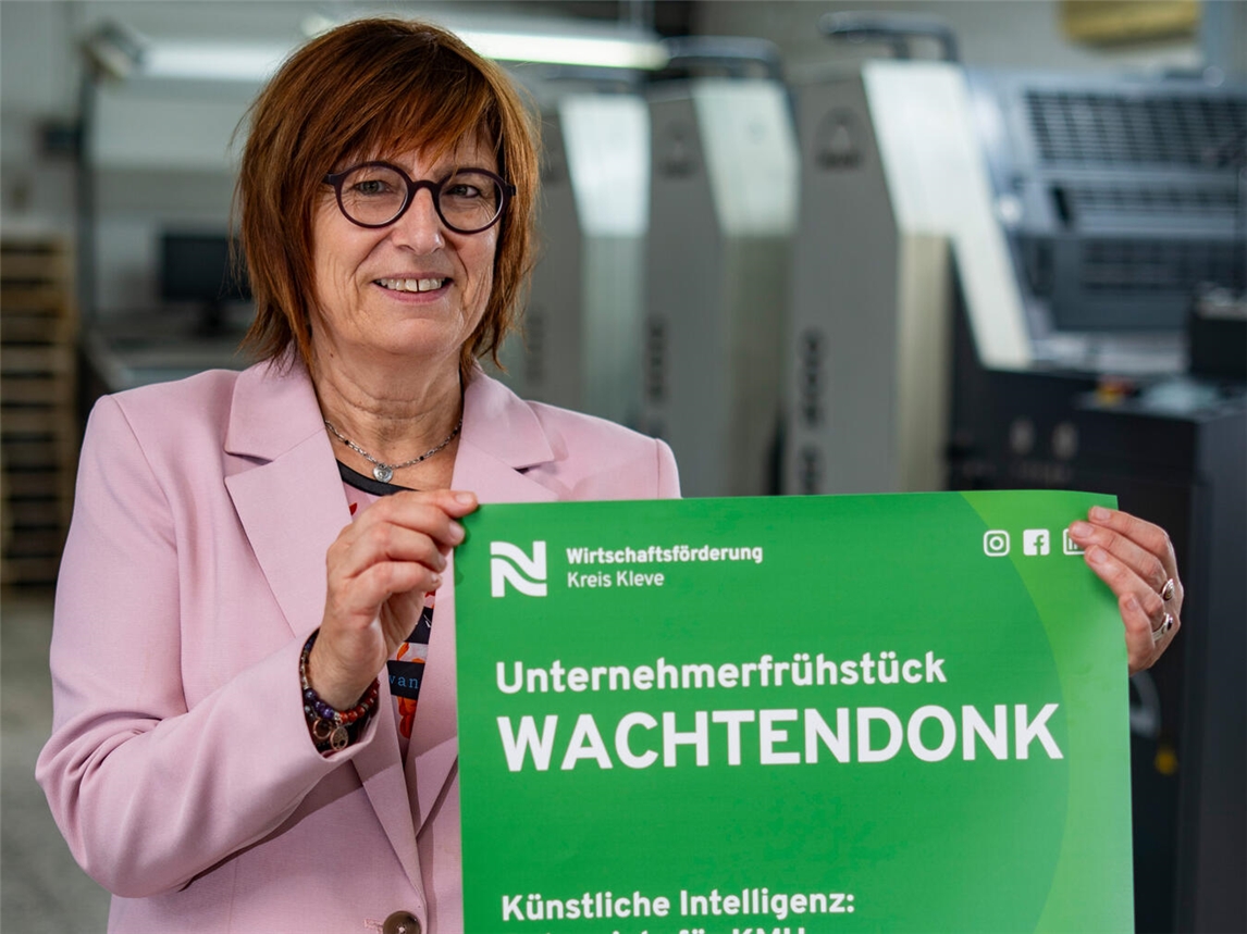 Brigitte Jansen, Geschäftsführerin der Wirtschaftsförderung Kreis Kleve, präsentiert das Plakat mit der Einladung zum Unternehmerfrühstück in Wachtendonk.Foto: WfG Kreis Kleve