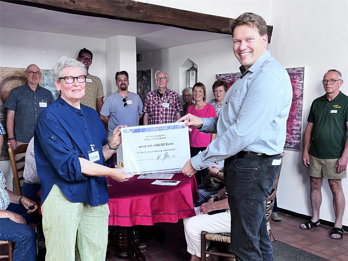 Brigitte Weyers (l.) nimmt den Gutschein von Stefan Mülders (r.) stellvertretend für das gesamte Team des Repair-Cafés Kalkar entgegen. Foto: Ellen Bosdorf-Schmidt/ KKA