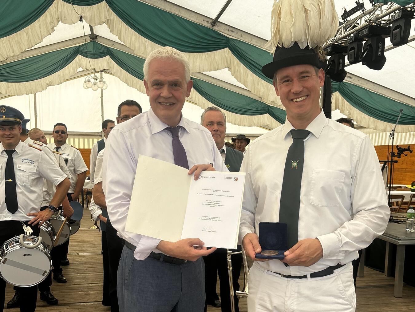 Brudermeister Bernd Enders und Dr. Günther Bergmann bei der Übergabe von Urkunde und Ehrenplakette im Schützenzelt. Foto: privat