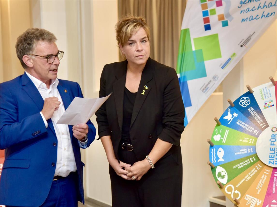 Bürgermeister Dietmar Heyde erklärte der nordrhein-westfälischen Ministerin für Wirtschaft, Industrie, Klimaschutz und Energie und stellvertretenden Ministerpräsidentin, Mona Neubaur, die Nachhaltigkeitsziele der Stadt Rheinberg „op Rhinberkse Platt“ anhand des „Rheinberger Nachhaltigkeitsglücksrads“. Foto: Stadt Rheinberg