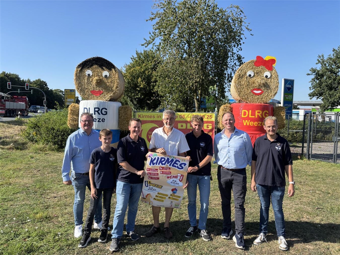 Bürgermeister Georg Koenen, Festkettenträger Christian Langenberg mit Sohn Jonas, der Vorsitzende der geselligen Vereine Wemb, Heinz-Theo van Wickeren, Adjutant Michael Denissen, der Vorsitzende des Heimat- und Verkehrsvereins Weeze, Marco Scuderi und Adjutant Tobias Küppers vor den Kirmes-Strohpuppen (v.l.n.r.). Foto: Gemeinde Weeze