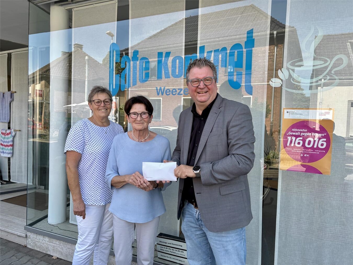 Bürgermeister Georg Koenen übergibt eine Spende an die Mitarbeiterinnen des Cafés Konkret, Angelika Reuters (mi.) und Maria van Straelen (li.). Foto: Gemeinde Weeze