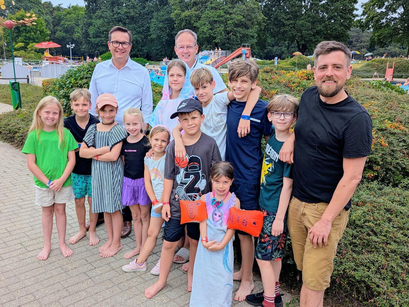 Bürgermeister Sven Kaiser (links) mit Markus Grönheim und Daniel Mommen (rechts) sowie einige glückliche Ferienkinder. NN-Foto: JK