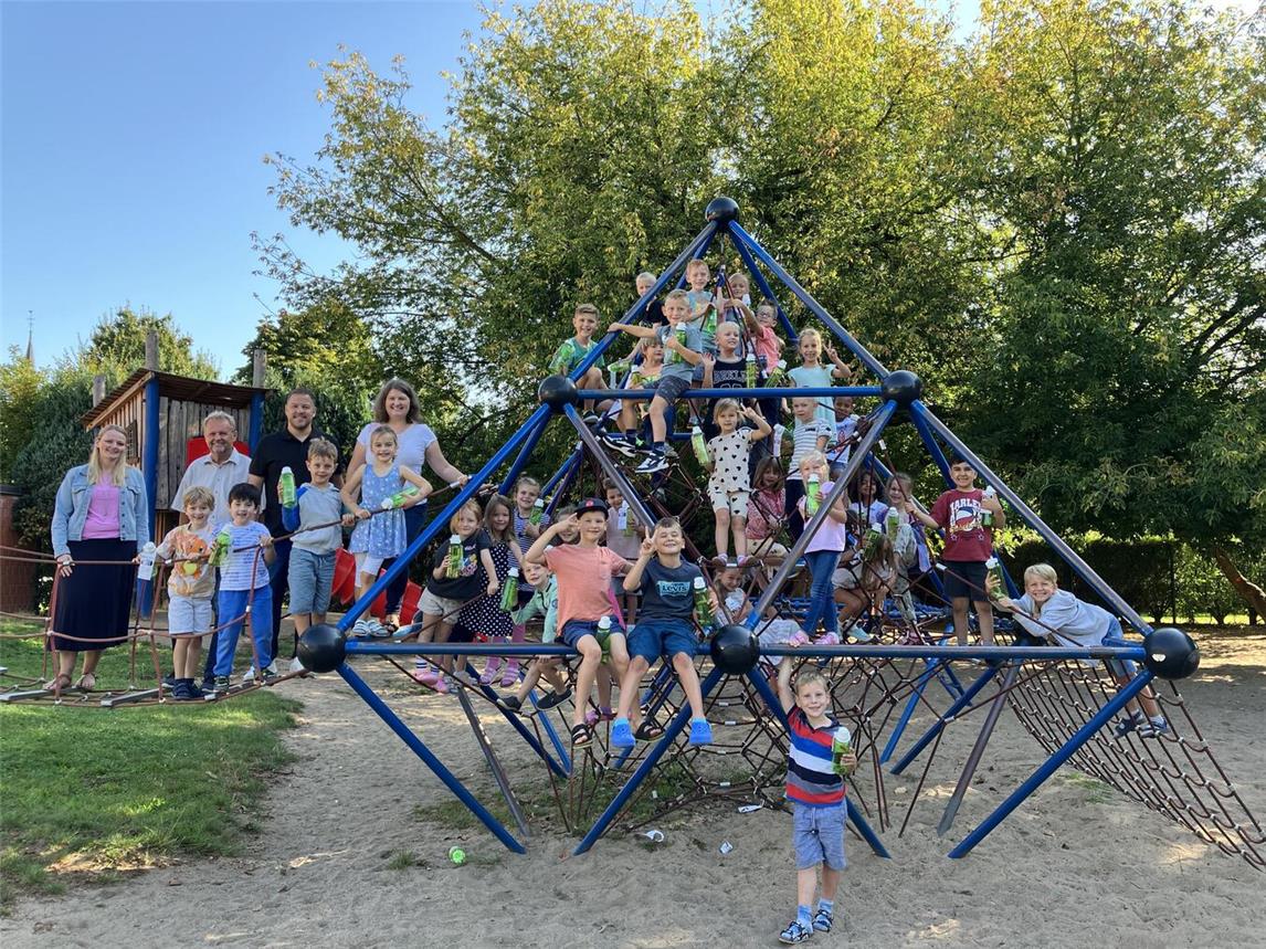 Bürgermeister Thomas Ahls (2. Reihe 2. v. l.), Nils Rudolph, Westenergie-Kommunalmanager (2. Reihe 3. v. l.), Rektorin Frauke Hegmann (2. Reihe 4. v. l.) und Konrektorin Tanja Hörath (2. Reihe l.) bei der Übergabe der Westenergie Trinkflaschen an die 65 Erstklässlerinnen und Erstklässler der GGS Alpen. Foto: Westenergie AG