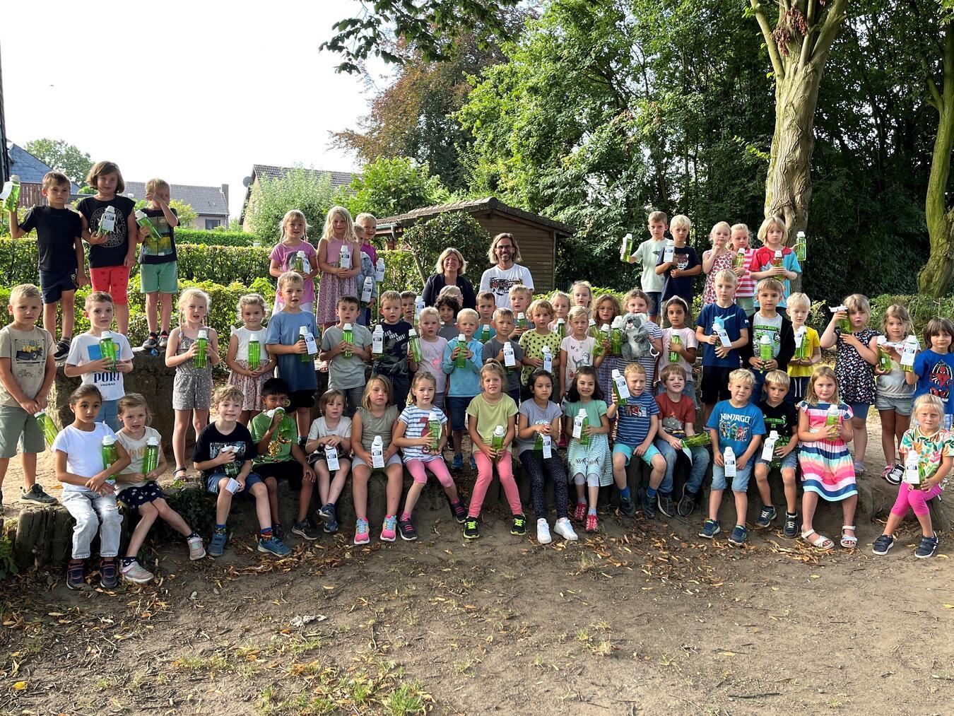 Bürgermeisterin Nadine Bogedain (hinten Mitte l.) überreichte gemeinsam mit der Westenergie die Trinkflaschen an Schulleiter Matthias Kamps (hinten Mitte r.) und die über 80 Erstklässler. Foto: Westenergie AG