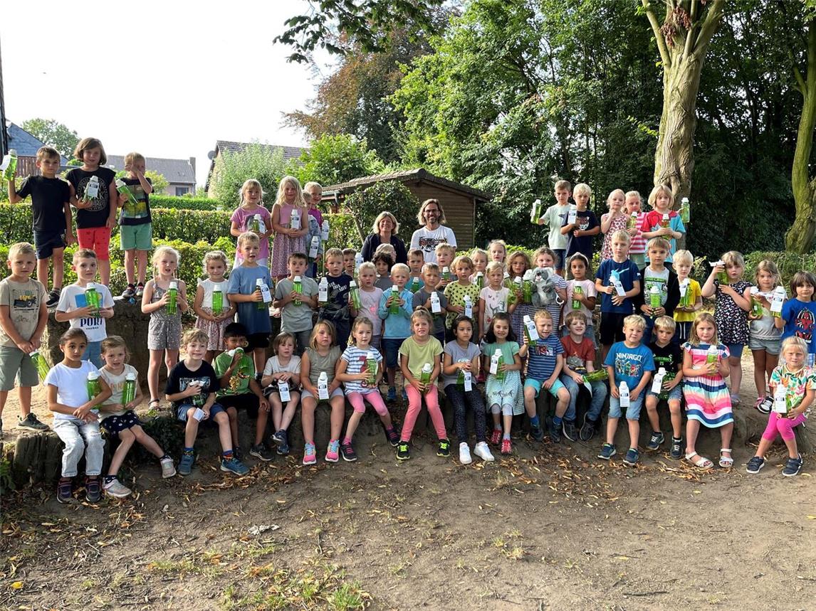 Bürgermeisterin Nadine Bogedain (hinten Mitte l.) überreichte gemeinsam mit der Westenergie die Trinkflaschen an Schulleiter Matthias Kamps (hinten Mitte r.) und die über 80 Erstklässler. Foto: Westenergie AG