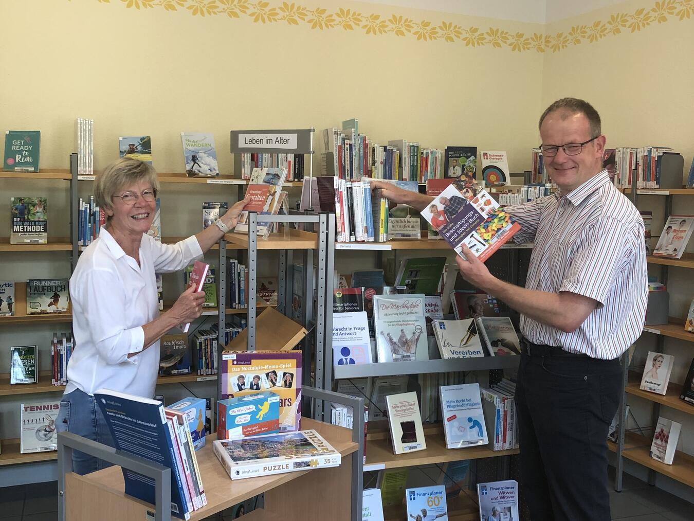 Claudia Breuer und Thomas Dierkes von der Reeser Stadtbücherei richten die Demenz-Themenecke mit den Sachspenden ein. Foto: Stadt Rees