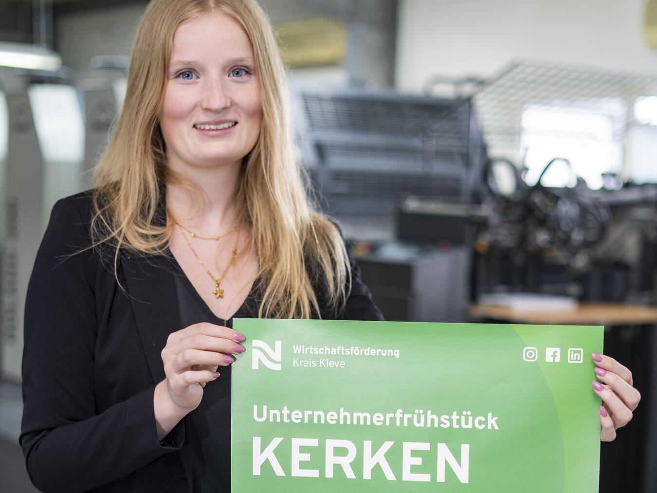 Corinna Strunk von der Wirtschaftsförderung Kreis Kleve präsentiert das Plakat mit der Einladung zum Unternehmerfrühstück in Kerken.Foto: Kreis-WfG/GS