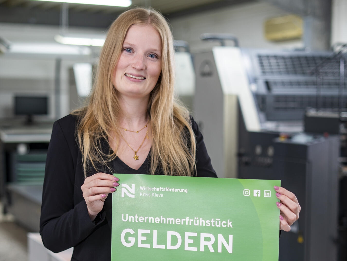 Corinna Strunk von der Wirtschaftsförderung Kreis Kleve präsentiert das Plakat mit der Einladung zum Unternehmerfrühstück in Geldern.Foto: WfG Kreis Kleve