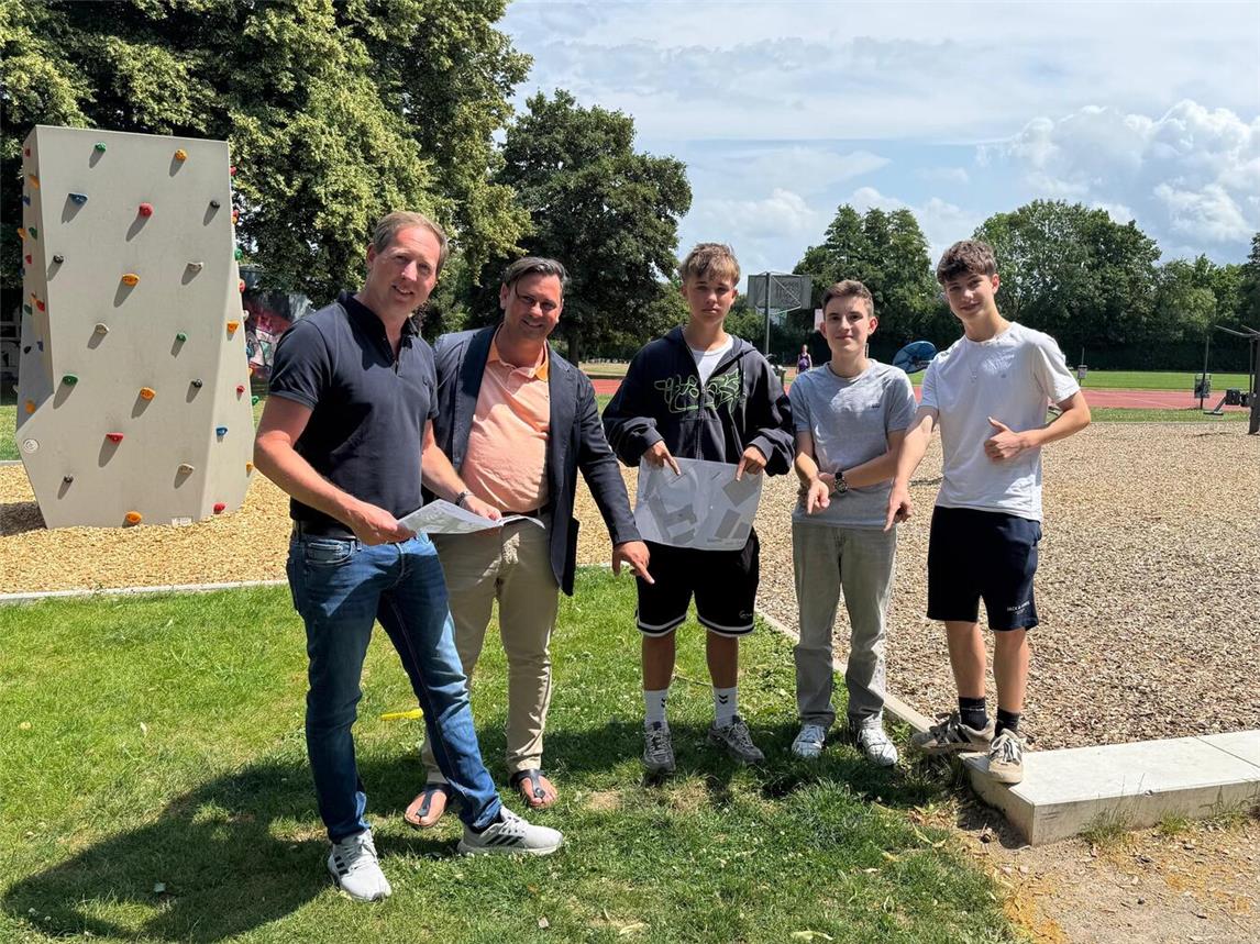 Daniel Bousart von den Stadtwerken (l.), Denis Erbozkurt-Becker vom Team Jugendhilfeplanung der Stadt Geldern (2.v.l.) sowie die Schüler des Friedrich-Spee-Gymnasiums haben schon einen guten Platz für den Trinkwasserspender gefunden.Foto: Stadt Geldern/Gossens
