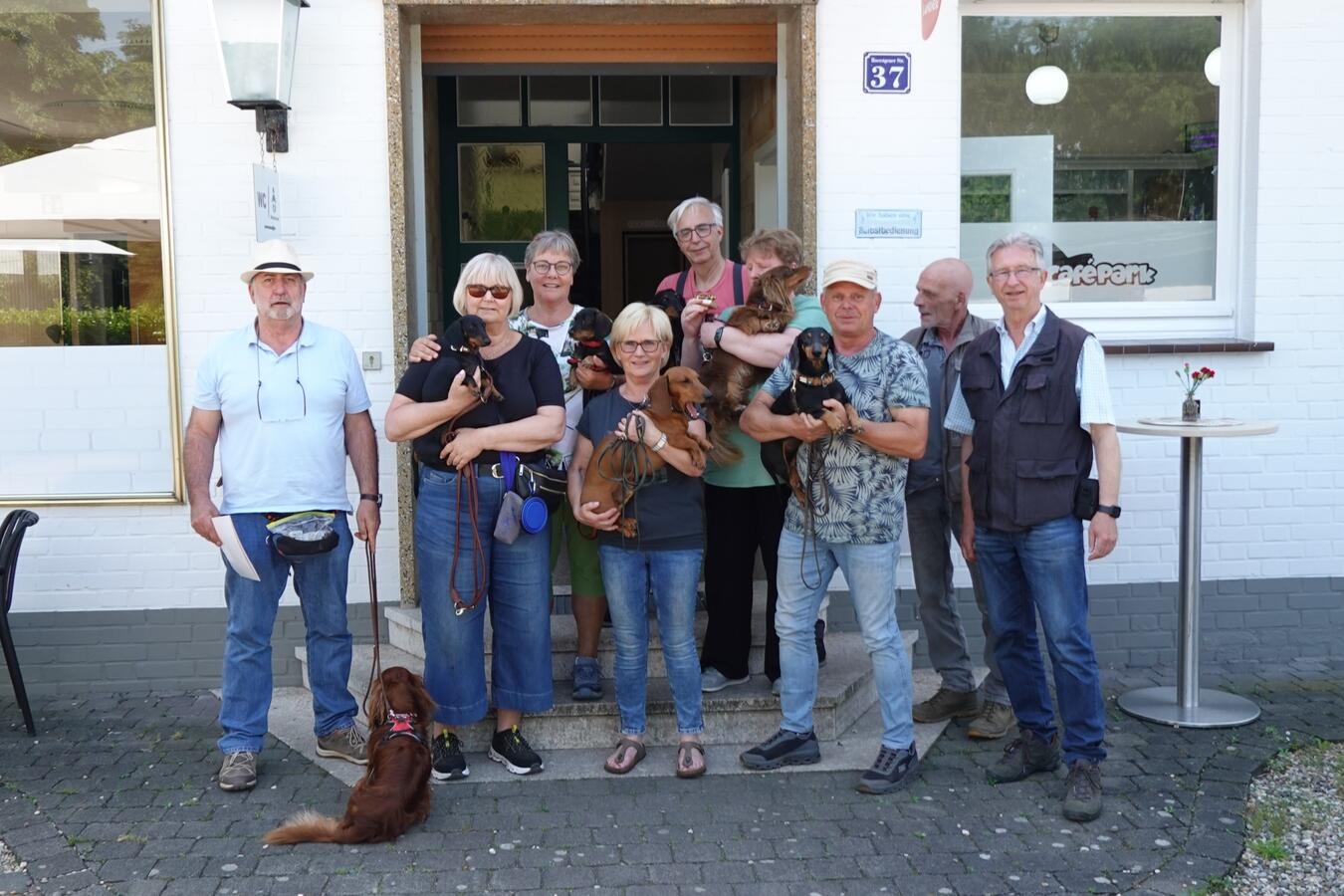 Gruppenfoto von sieben Erwachsenen und sechs Kindern im Freien, fröhlich lächelnd. Familienausflug, Gemeinschaft, Zusammenhalt.