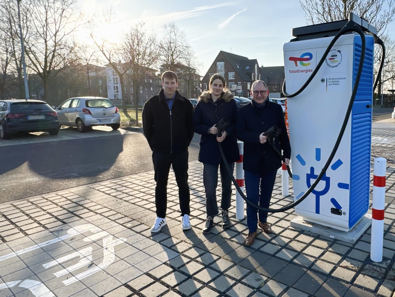 Das Laden für Elektroautos ist jetzt an den Energiestationen auf dem Parkplatz am Schulzentrum in Rees möglich: (v. re.) Bürgermeister Sebastian Hense, Klimaschutzmanagerin Christine Klanten und Erik Käsbach (TotalEnergies). Foto: Stadt Rees