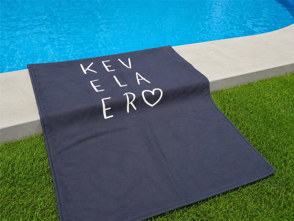 Das Merch des Monats in Kevelaer ist dieses Mal ein Handtuch. Foto: Wallfahrtsstadt Kevelaer (Hintergrund mit KI bearbeitet)