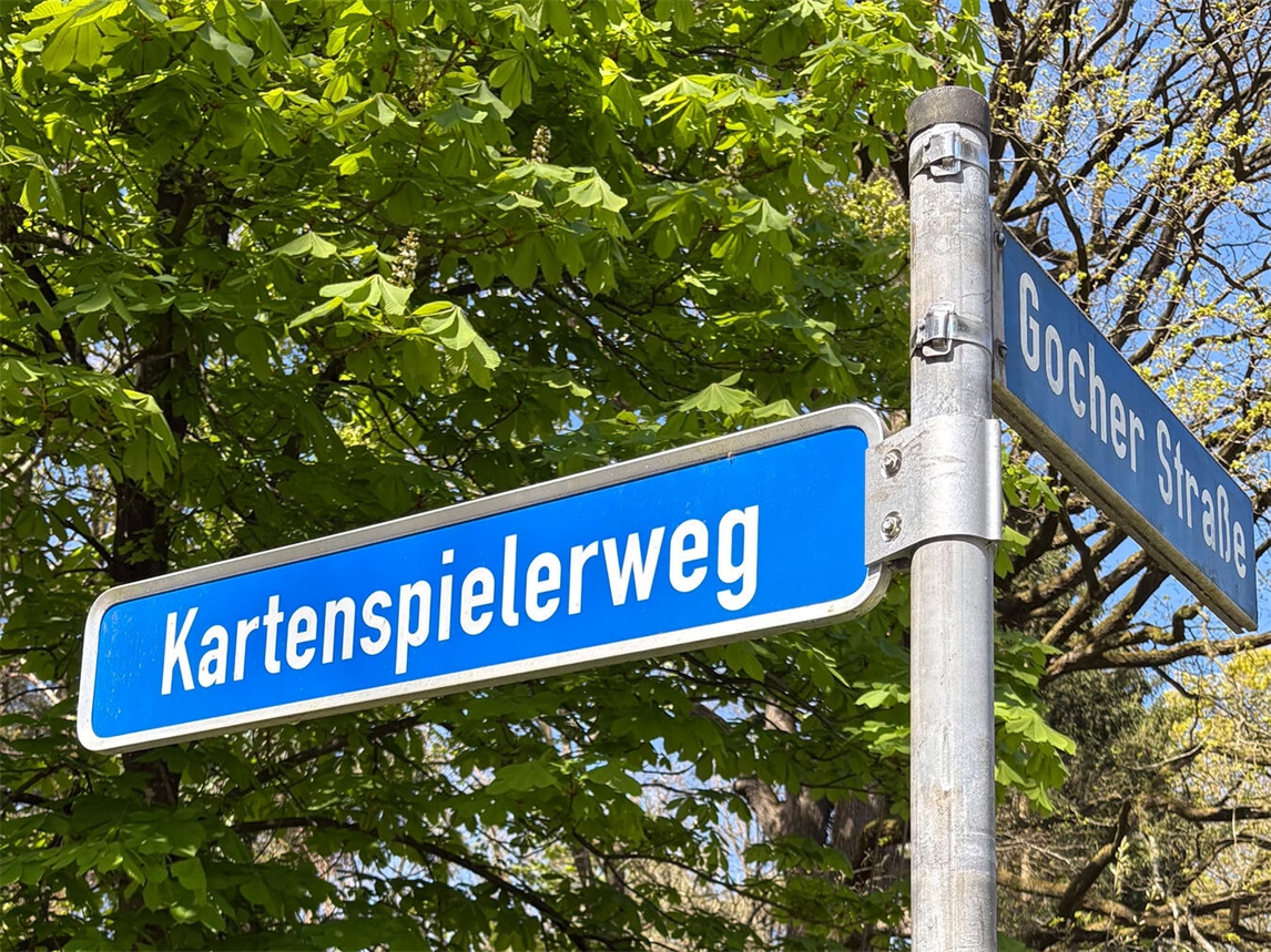 Straßenschild am Kartenspielerweg bei sonnigem Wetter, Foto von Katrin Düngel.