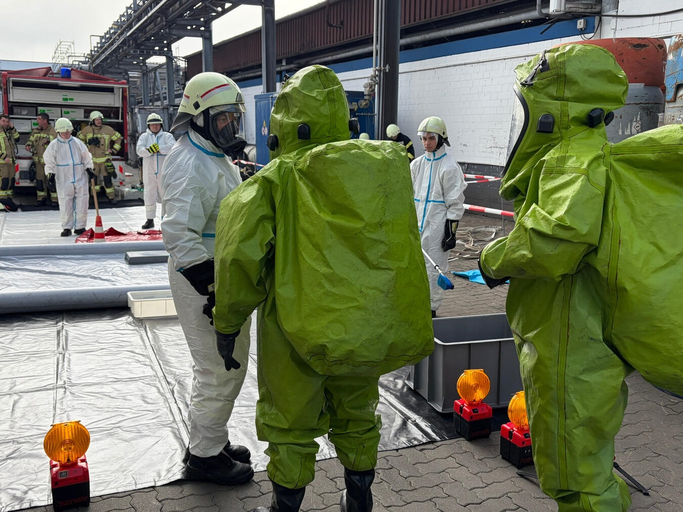 "Einsatzkräfte bei Dekontamination im Schutzanzug, Sicherheitsmaßnahmen"