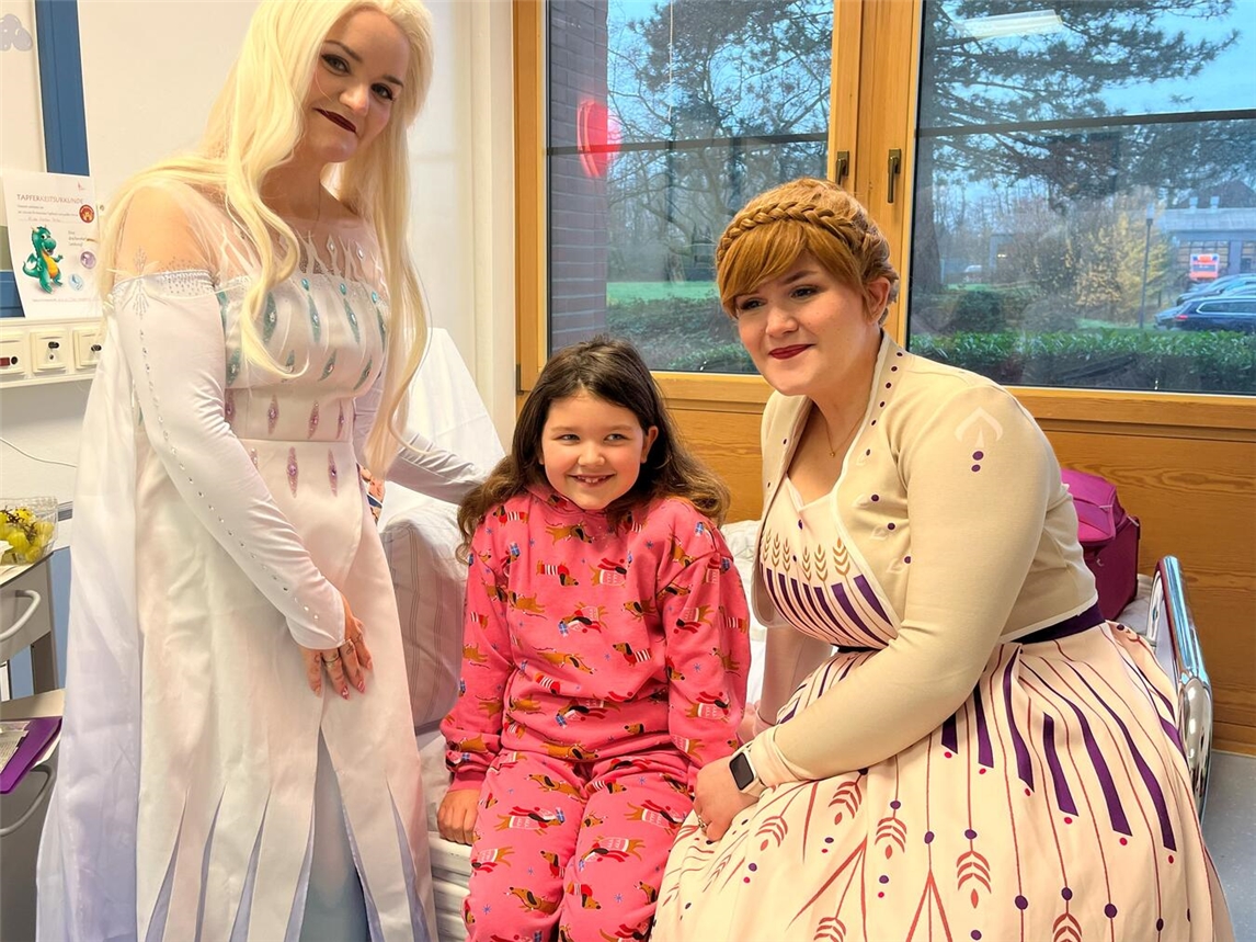Denise Winkels als Elsa und ihre Schwester Desiree Claus als Anna vom Kinderanimationsteam Stern-Magie zaubern Patientin Frieda in der Klinik für Kinder und Jugendliche des St.-Clemens-Hospitals Geldern ein Lachen ins Gesicht.Foto: St.-Clemens-Hospital
