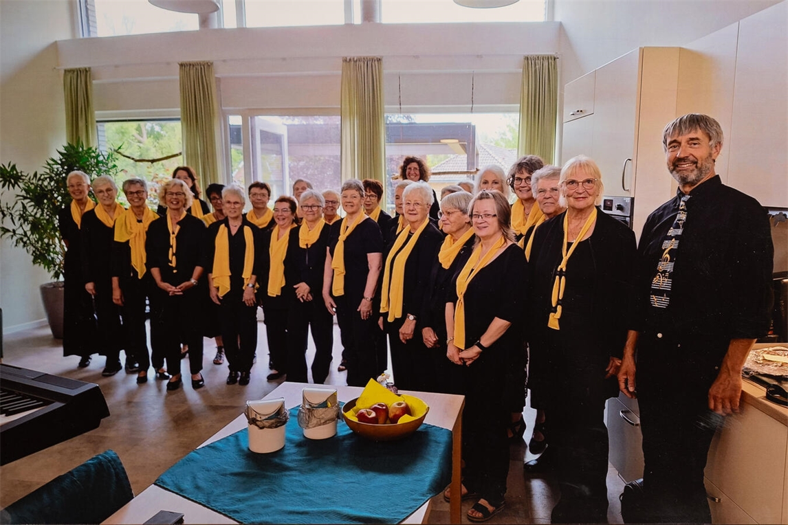"Frauenchor mit Chorleiter Manfred Hendricks lächelt, wartet auf Besucher, Chormusik Event."