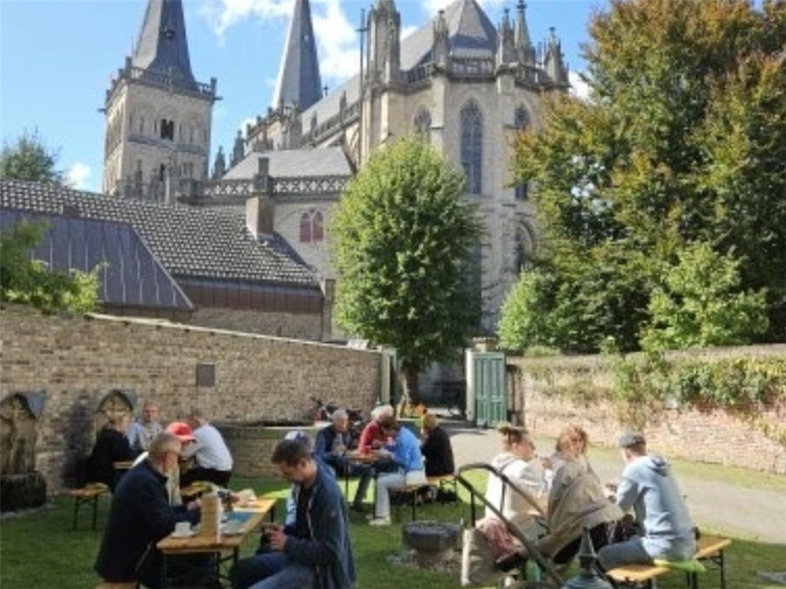 "Geöffneter Garten der Kanonikerkurie am Tag des Denkmals, üppige Vegetation, ruhige Atmosphäre"