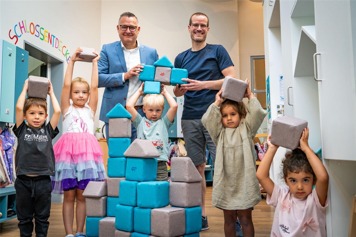 "Geschäftsstellenleiter Björn Pusnik und Kita-Leiter Dominik Winkels mit Kindern, Volksbank an der Niers"